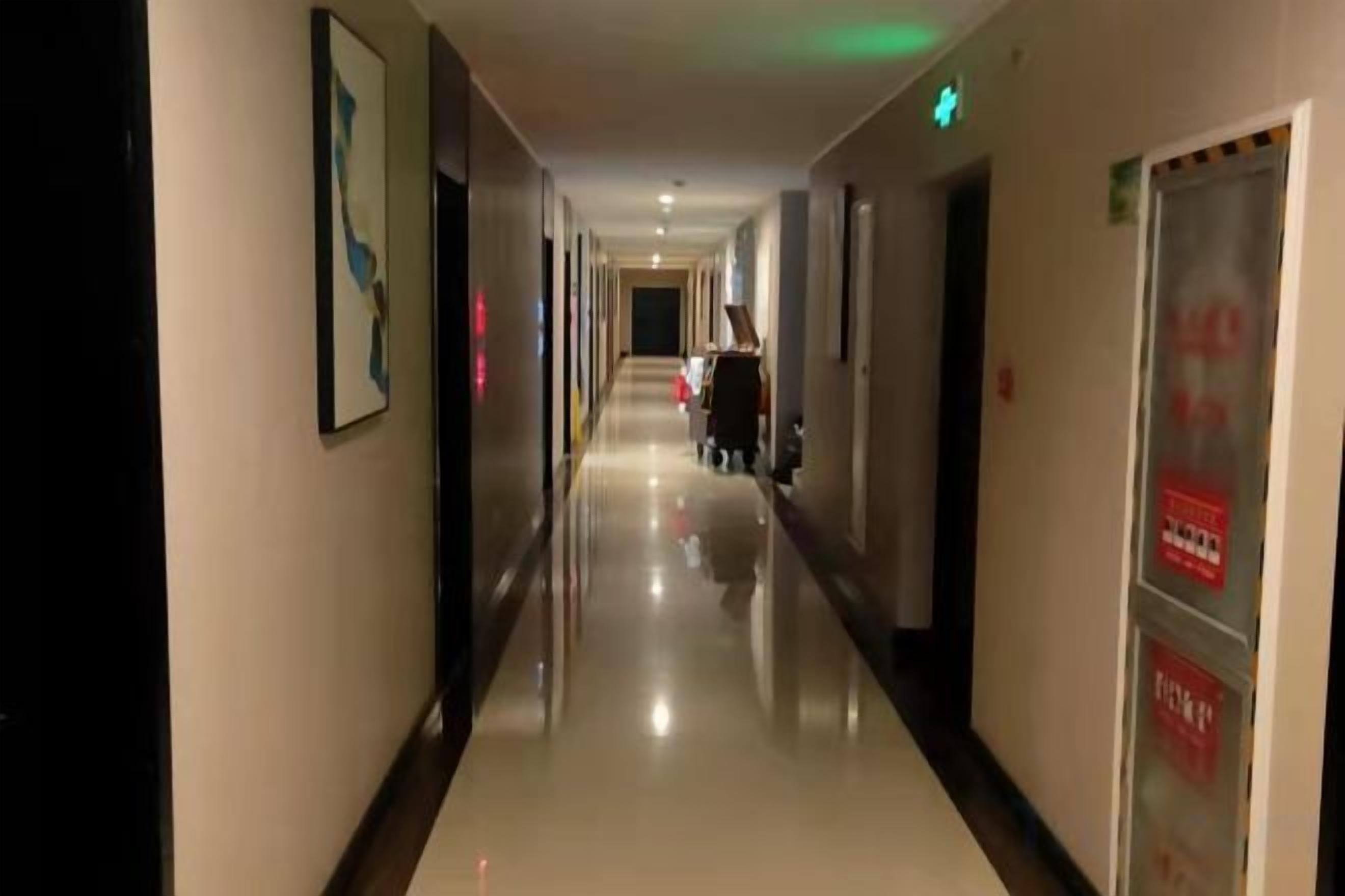 A hotel corridor with framed artwork on the walls, a polished floor, and directional signs.