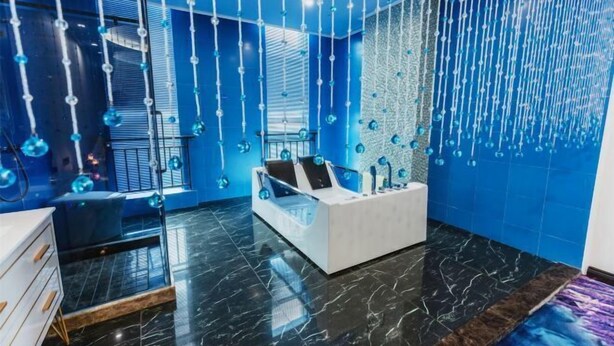 A modern hotel room with a white reception desk, a glass partition, and a blue wall with hanging decorations. - Zhoushan Xinxiting Grand Hotel (Zhoushan)