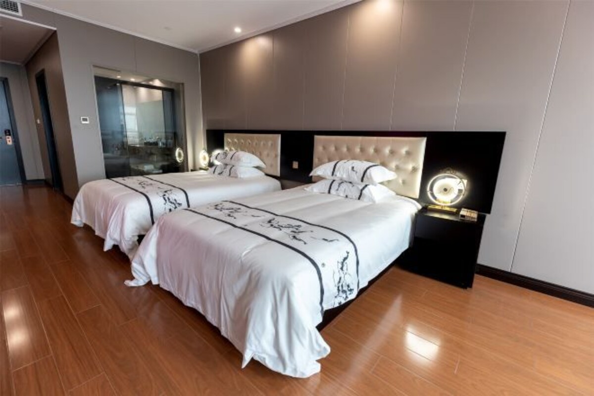 Habitación de hotel con dos camas, un espejo grande y un diseño moderno.