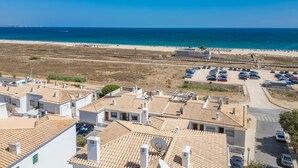 Una zona residenziale sulla costa, con case a tetto in terracotta, una spiaggia e un parcheggio.
