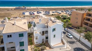 Una zona residenziale costiera caratterizzata da edifici bianchi, una spiaggia e un parcheggio.