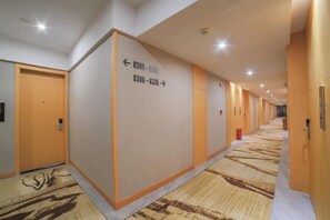A hotel corridor with directional signs, doors, and a patterned carpet. - Xidiya Business Hotel (Yichun Drum Tower Pedestrian Street Runda International) (Yichun)