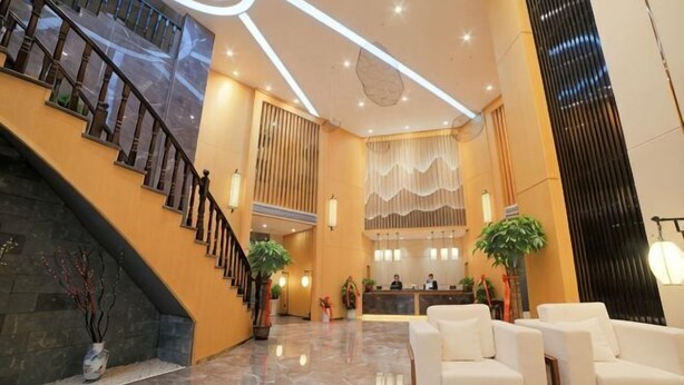 Un vestíbulo con una escalera, mostrador de recepción y zona de estar.