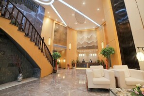 Un vestíbulo con una escalera, mostrador de recepción y zona de estar.