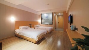 Habitación de hotel con dos camas, un televisor de pantalla plana montado en la pared y suelo de madera.