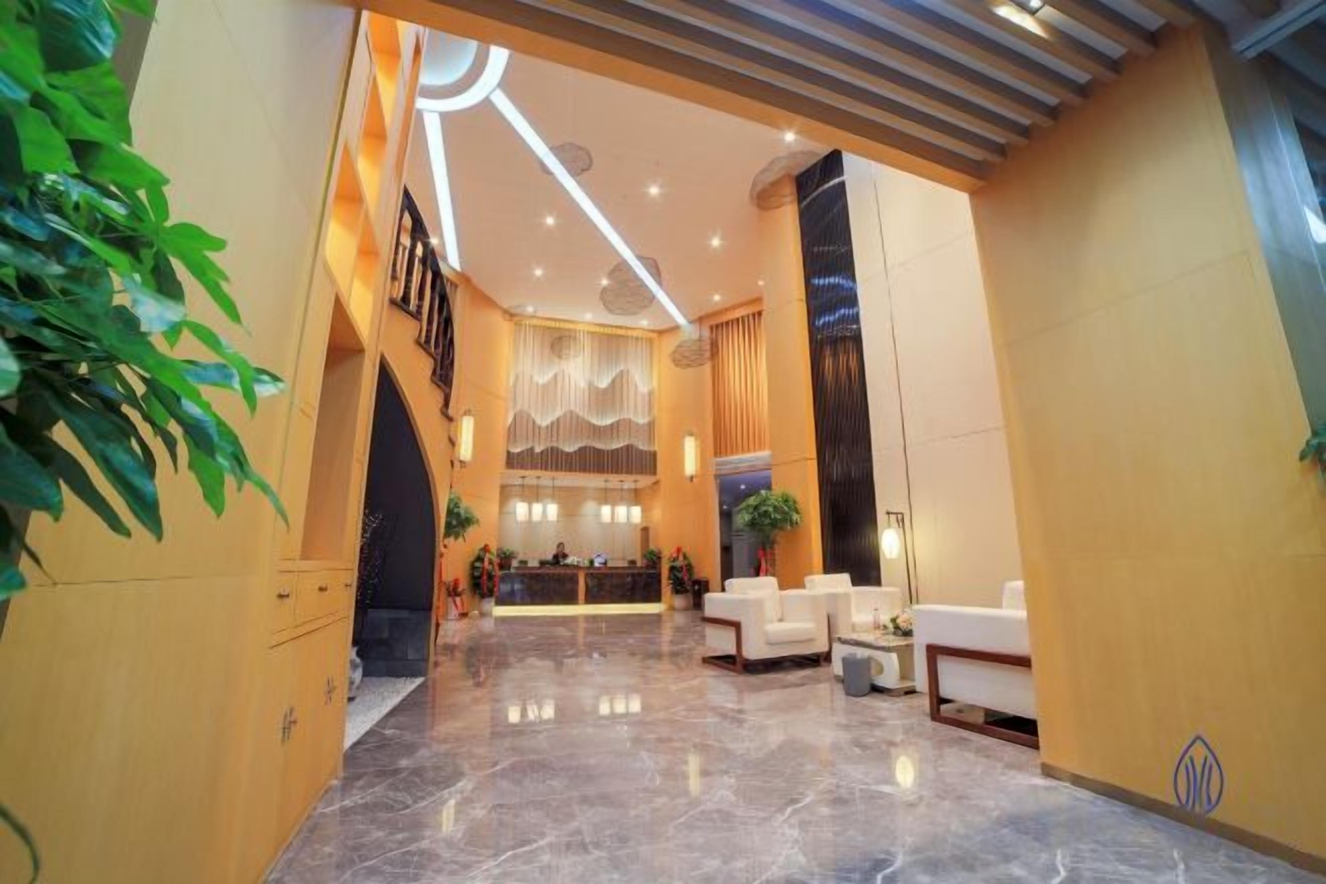 Un hall d’hôtel comprenant un comptoir d’accueil, un espace salon et un escalier.