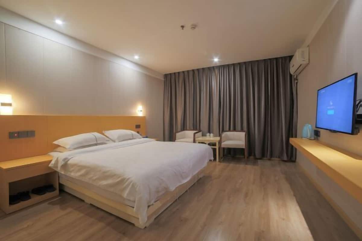 Una habitación de hotel moderna con una cama grande, mesitas de noche, televisión, escritorio y una silla.