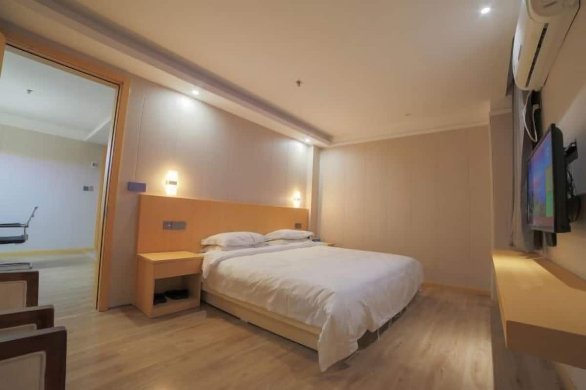 Un dormitorio con cama, mesitas de noche, televisor y aire acondicionado instalado en la pared.