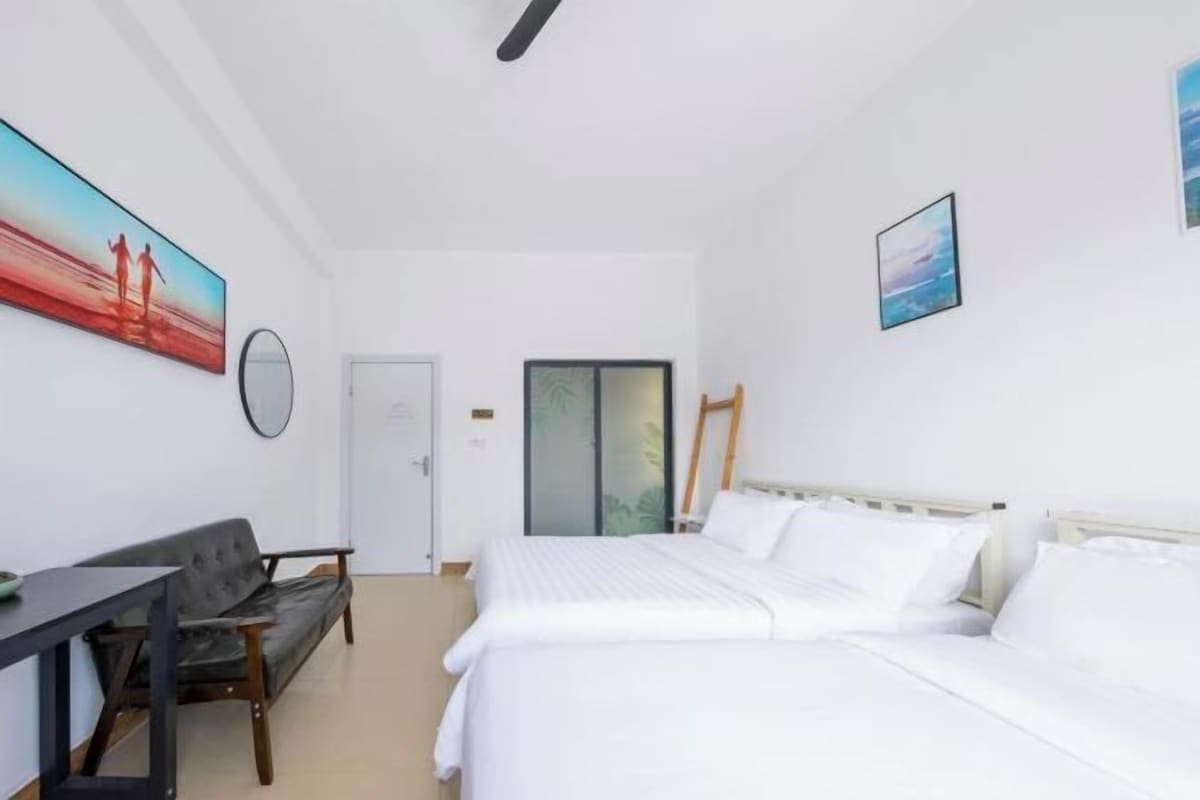 A hotel room with two beds, a desk, a chair, and artwork on the walls.