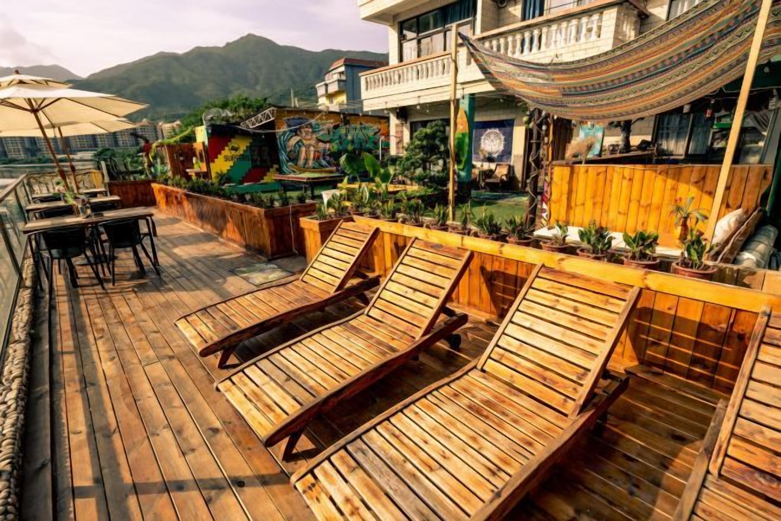 A wooden deck with lounge chairs, a hammock, and potted plants.