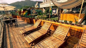 A wooden deck with lounge chairs, a hammock, and potted plants.