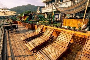 A wooden deck with lounge chairs, a hammock, and potted plants. - Time and Sea Inn (Shenzhen)