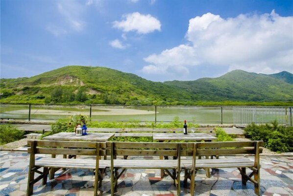 A wooden bench overlooking a river with a mountainous backdrop.