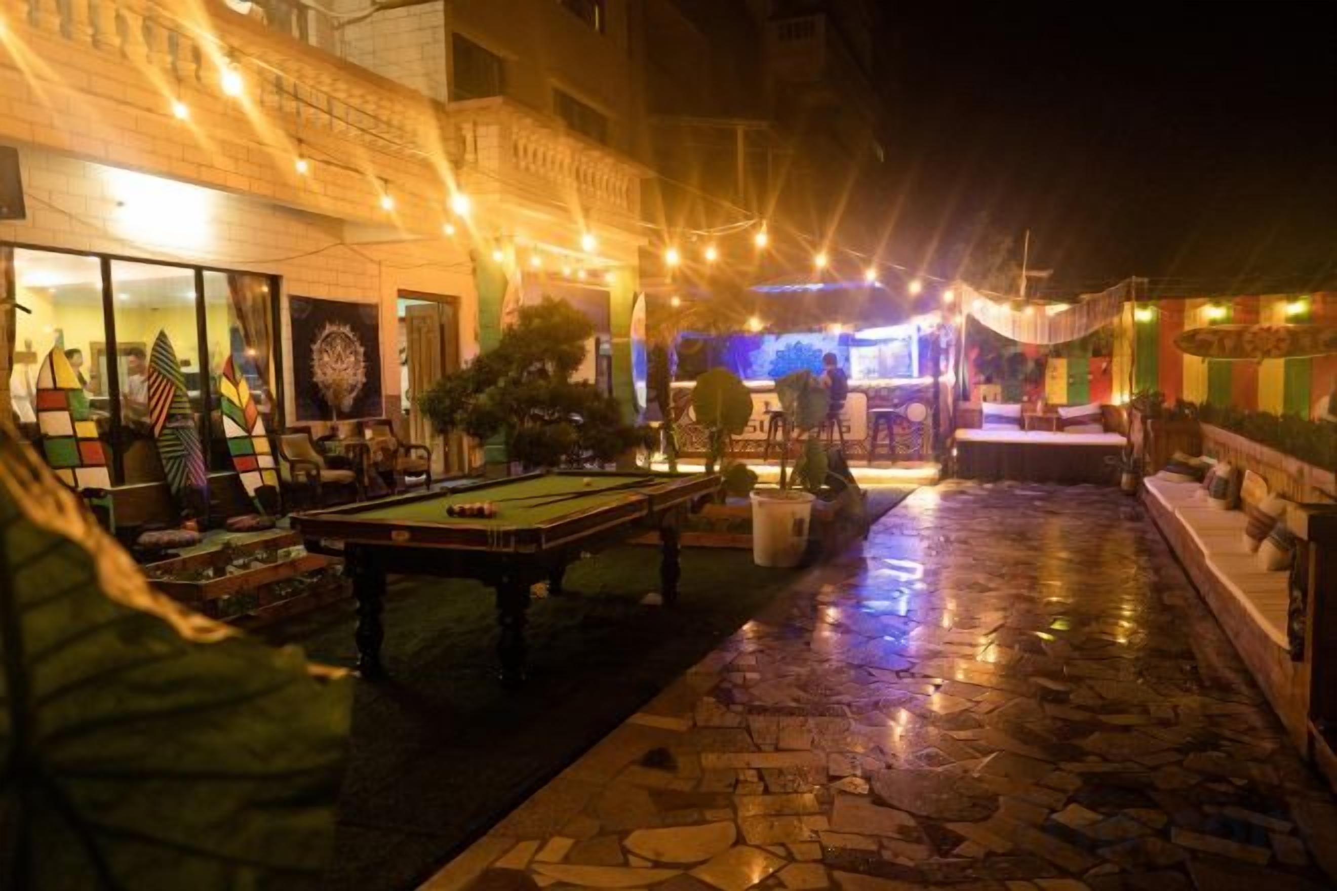 An outdoor pool area with a billiards table, string lights, and a stage for events.