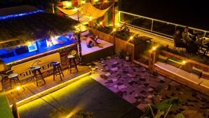 An outdoor seating area with a thatched roof, a bar area with stools, and a mosaic-tiled floor. - Time and Sea Inn (Shenzhen)
