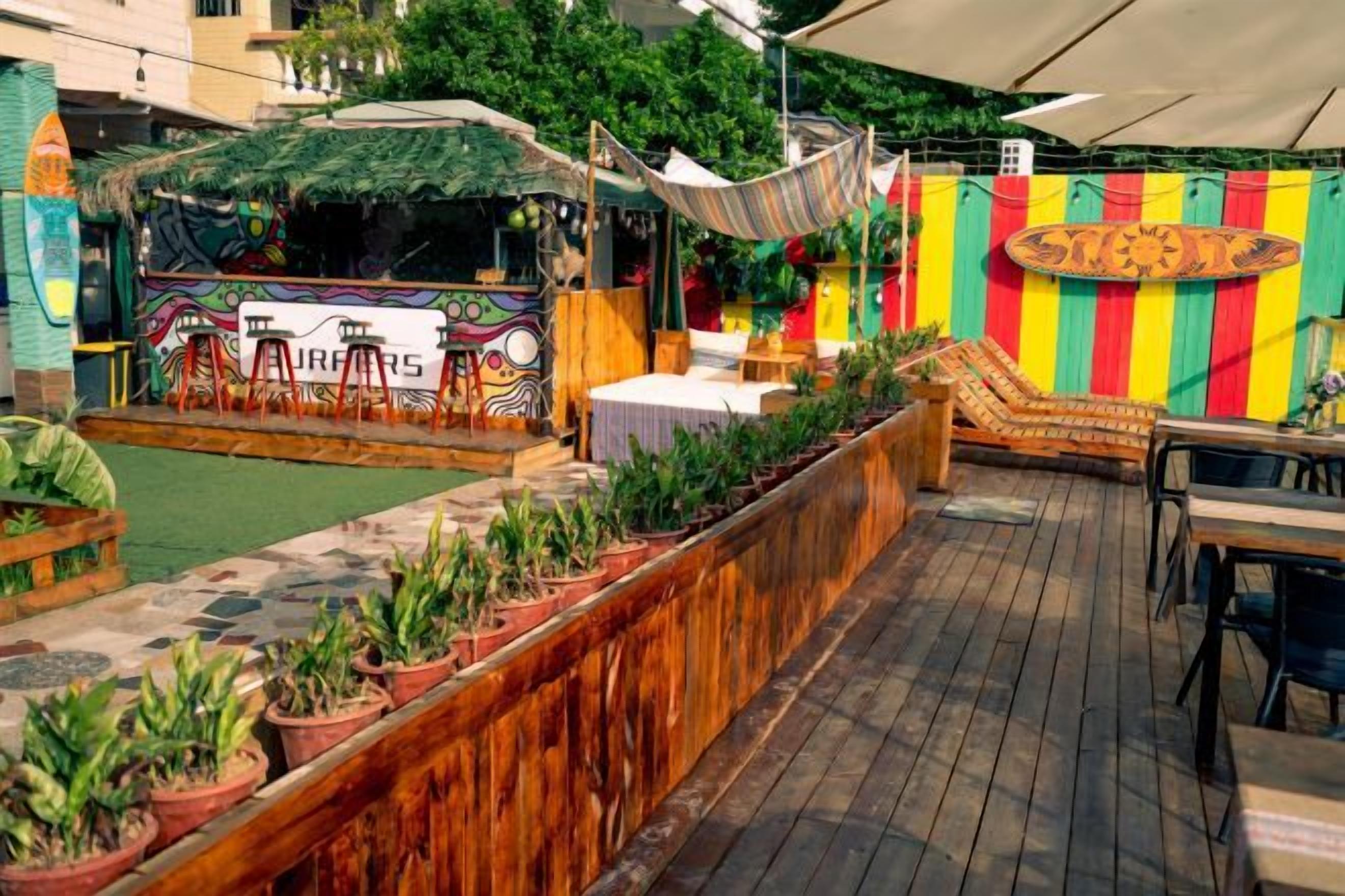 Un patio al aire libre con un escenario, asientos y una pared de rayas coloridas.