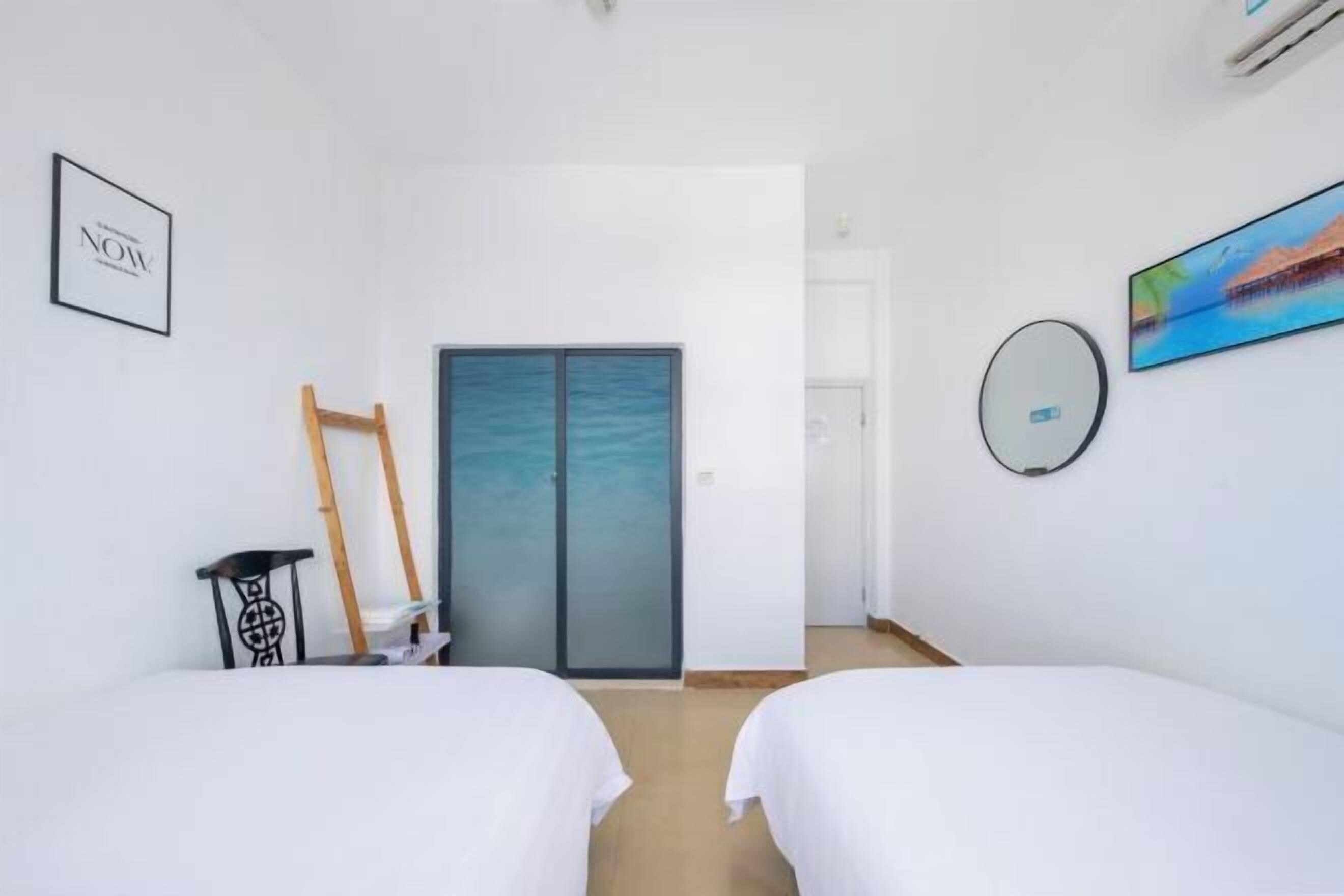 Habitación de hotel con dos camas, un armario, un espejo y un cuadro en la pared.