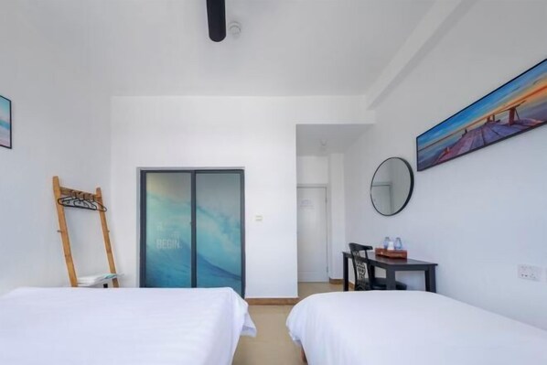 Habitación de hotel con dos camas, un escritorio, una silla, un espejo y un cuadro en la pared.