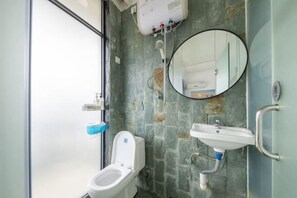 A bathroom with a toilet, a sink, a mirror, and a shower. - Time and Sea Inn (Shenzhen)