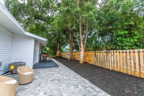 A patio with wicker furniture, a wooden fence, and trees.