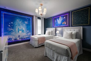 A bedroom with two beds, a chandelier, and themed wall art.