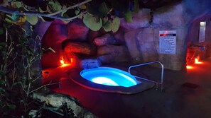 A spa area with a hot tub, a sign detailing spa rules, and a rock wall.