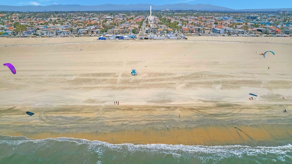 An aerial view of a beach with a cityscape in the background, including a prominent tower. - Villa La Verne (Long Beach)