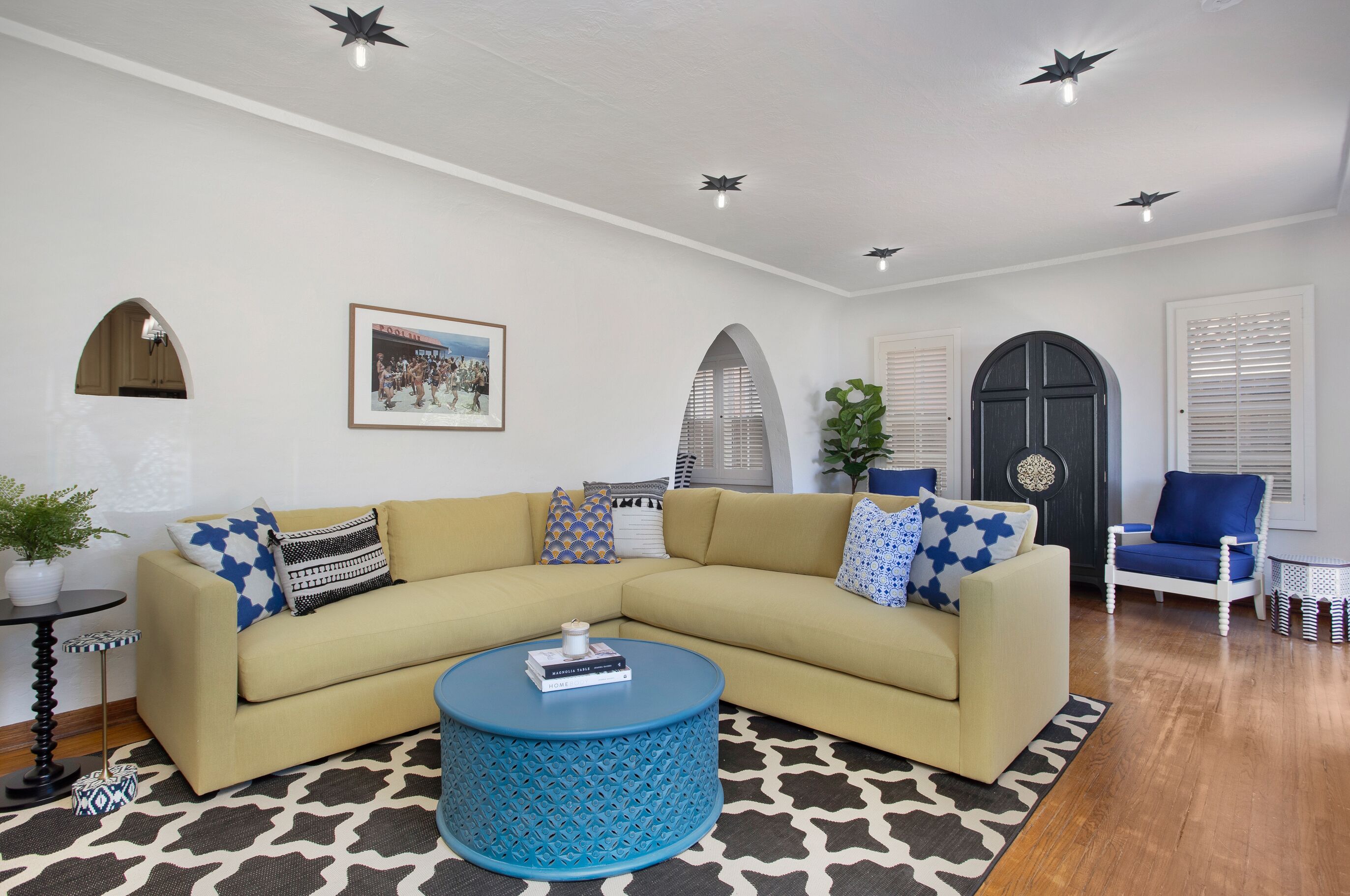 A living room with a beige sectional sofa, a blue coffee table, and a patterned rug.