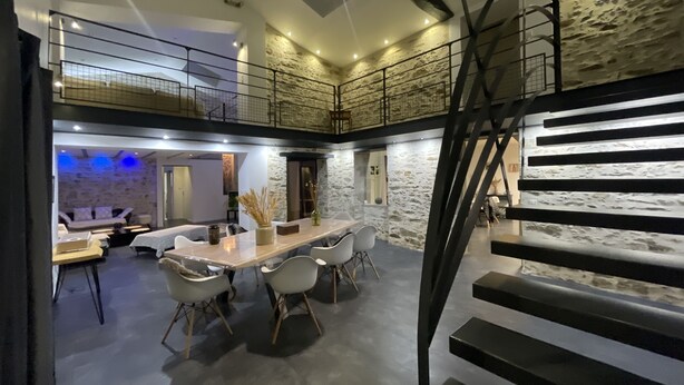 A modern interior with a dining area, a staircase, and a loft space.