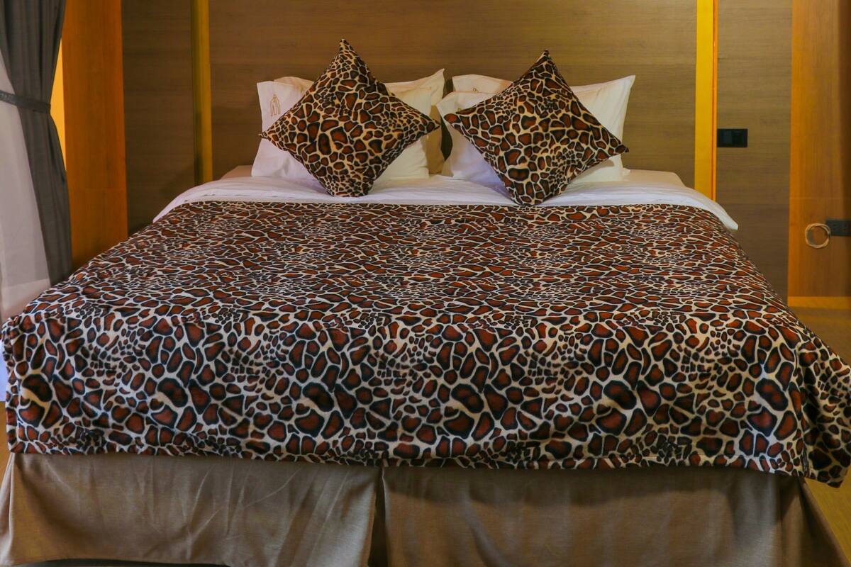 Una habitación de hotel con una cama grande, cabecera con lámpara y techo con cortinas.