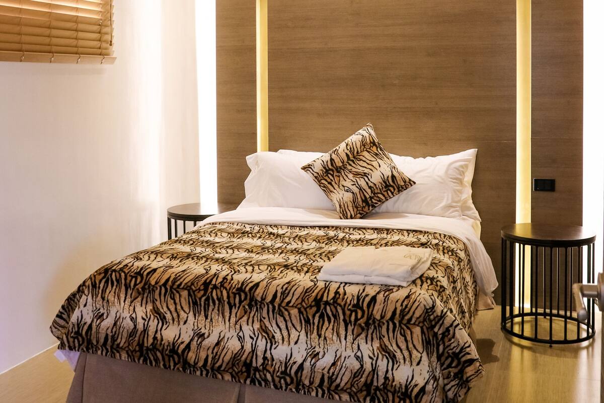 Un dormitorio moderno con una cama grande, cabecera de madera y una lámpara de techo.