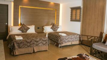 Quarto de hotel com duas camas, um guarda-roupa de madeira, um espaço de estar pequeno e um tapete de couro de vaca.