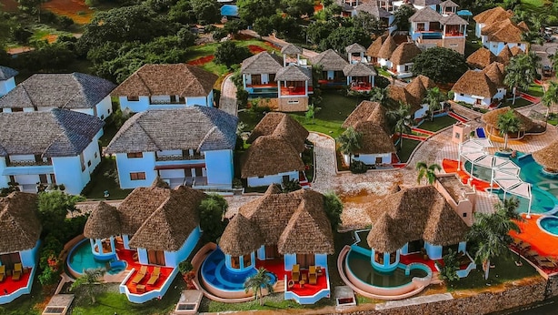 Een resort met rieten bungalows, een zwembad en uitzicht op de oceaan.