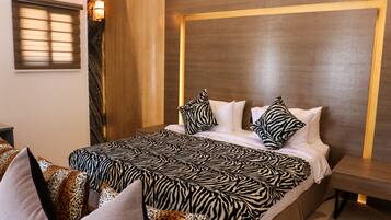A hotel room with a zebra-patterned bedspread, a wooden headboard, and a nightstand with a lamp.