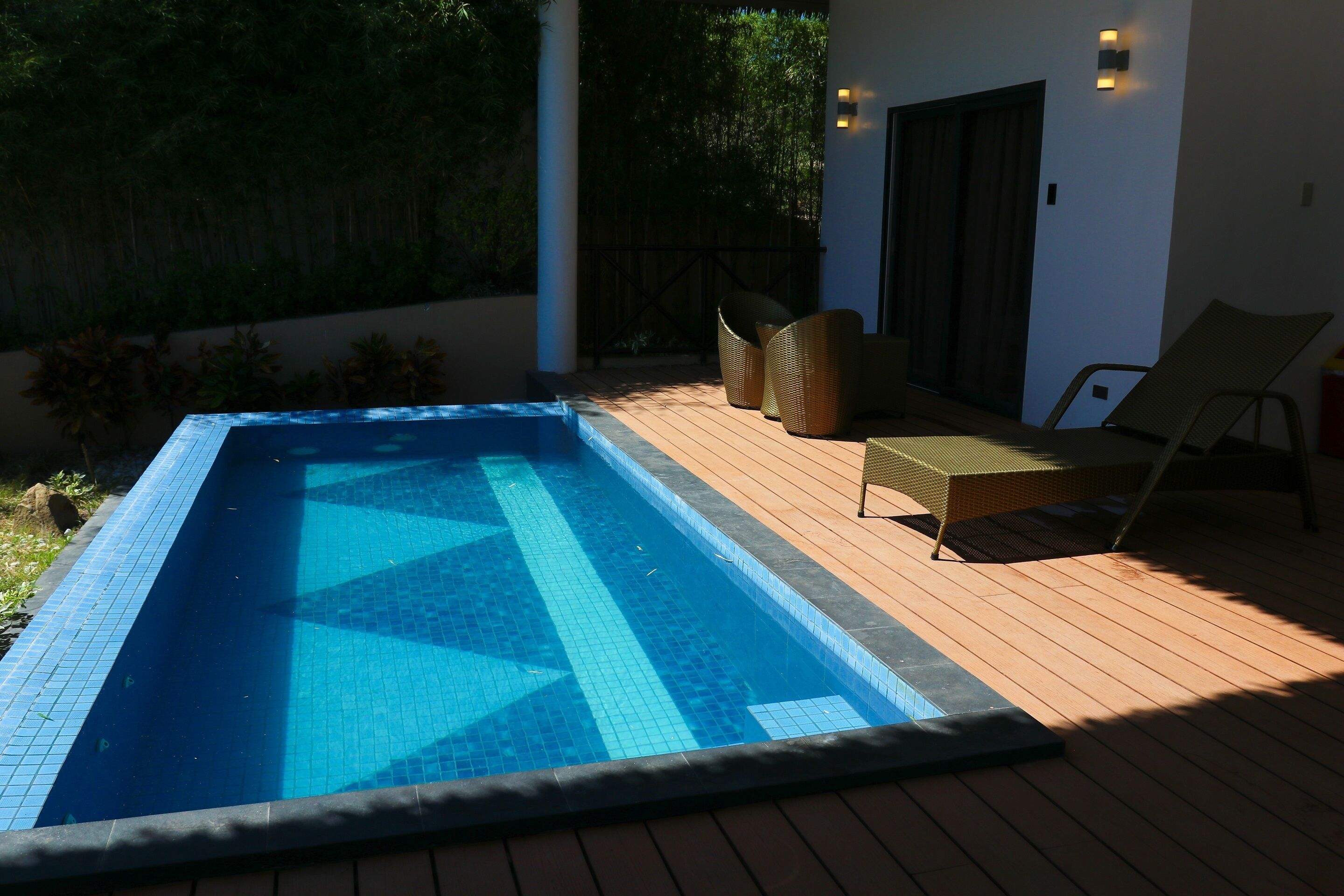 Una piscina rectangular con azulejos azules y un muelle de madera.