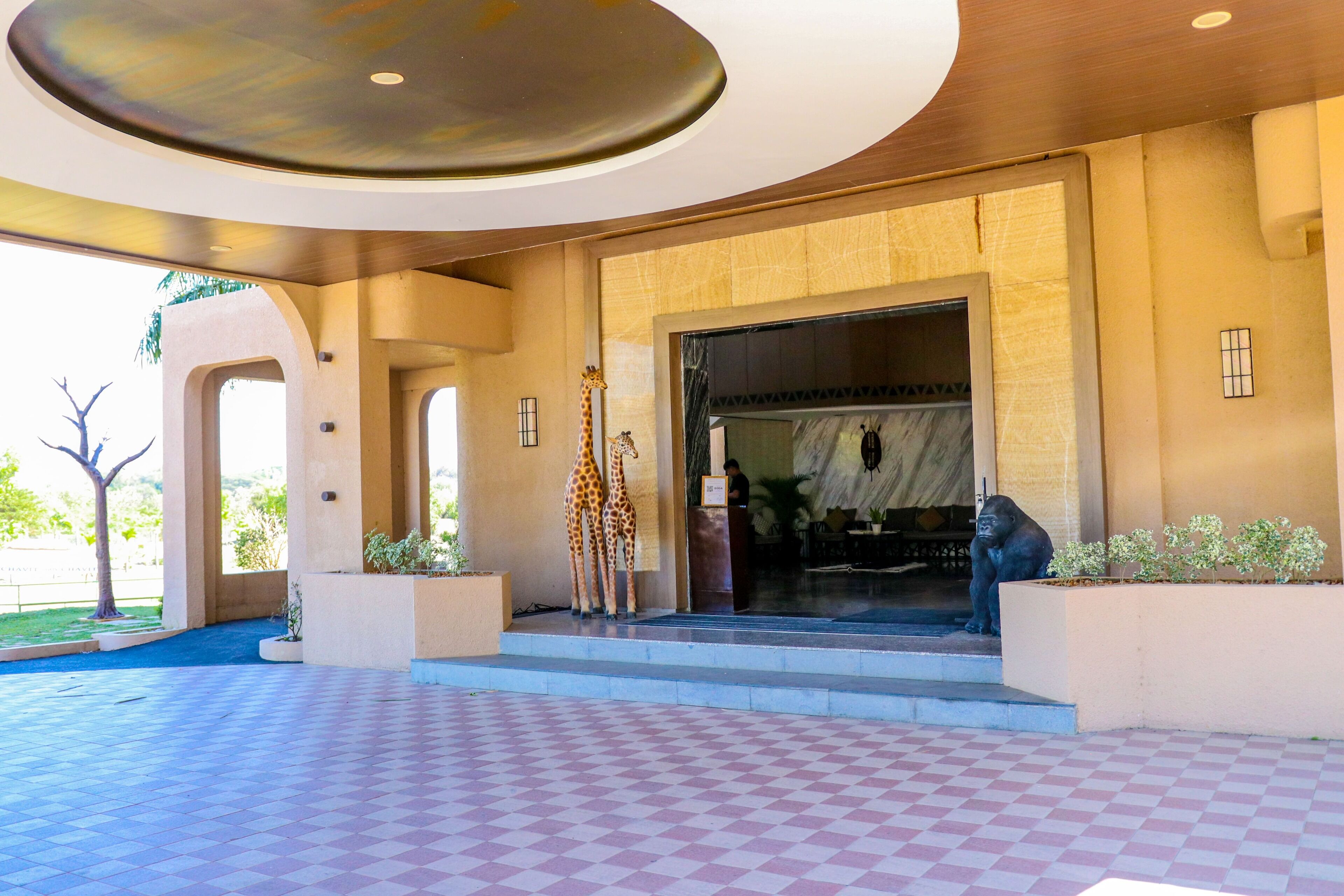A hotel entrance with a checkered floor, a large entrance door, and a statue of a gorilla.