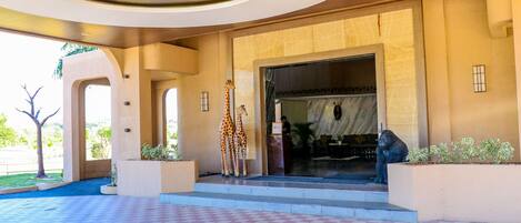 Una entrada de hotel con suelo a cuadros, una puerta principal grande y una estatua de un gorila.