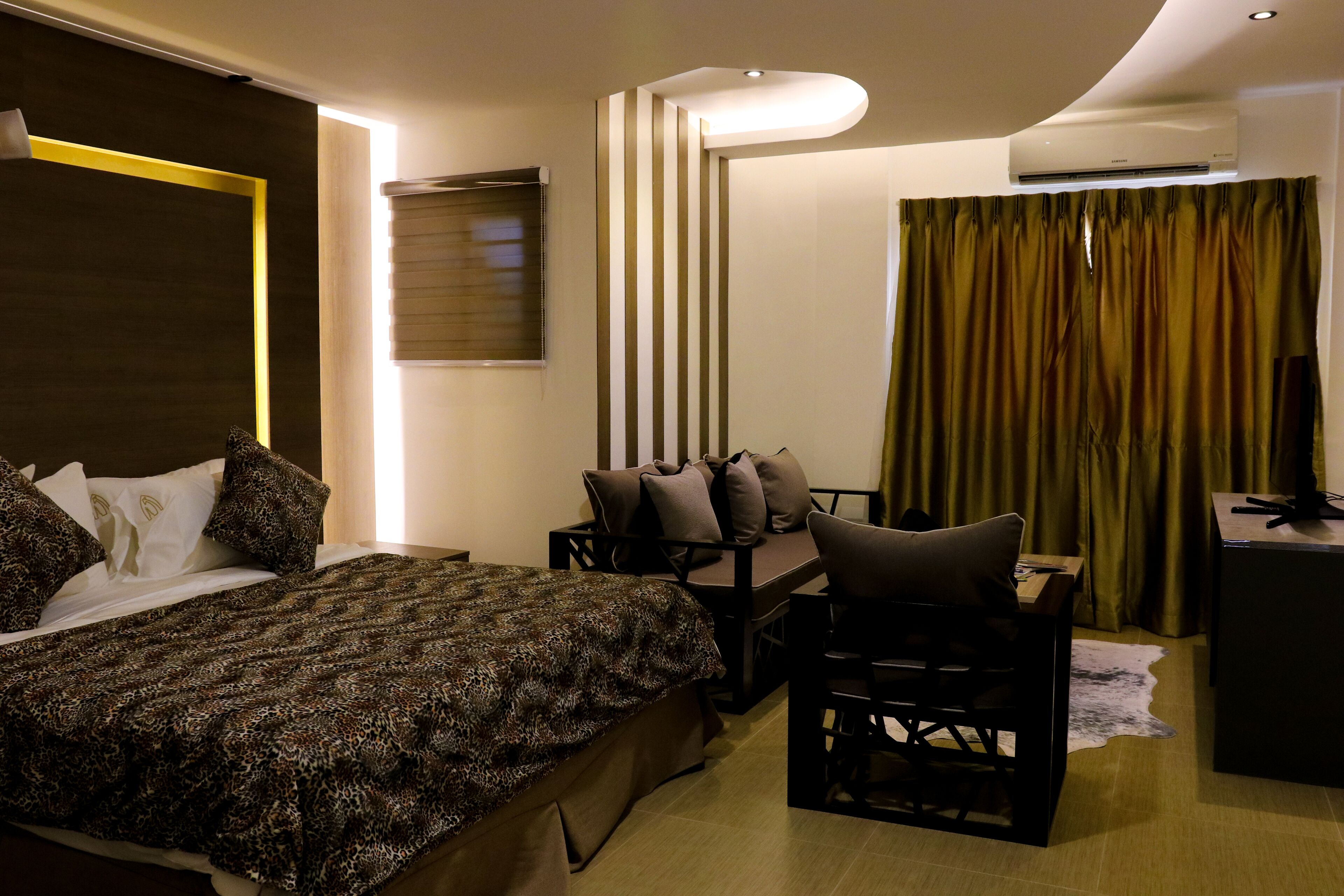 A hotel room with a bed, a desk, a chair, a television, and a curtain.
