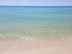 Une plage avec une eau claire et peu profonde et un rivage sablonneux.