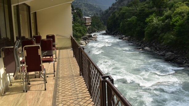 A balcony with a view of a river, chairs, and a railing.