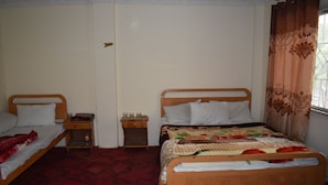 A bedroom with two wooden beds, a nightstand, and a window with curtains.