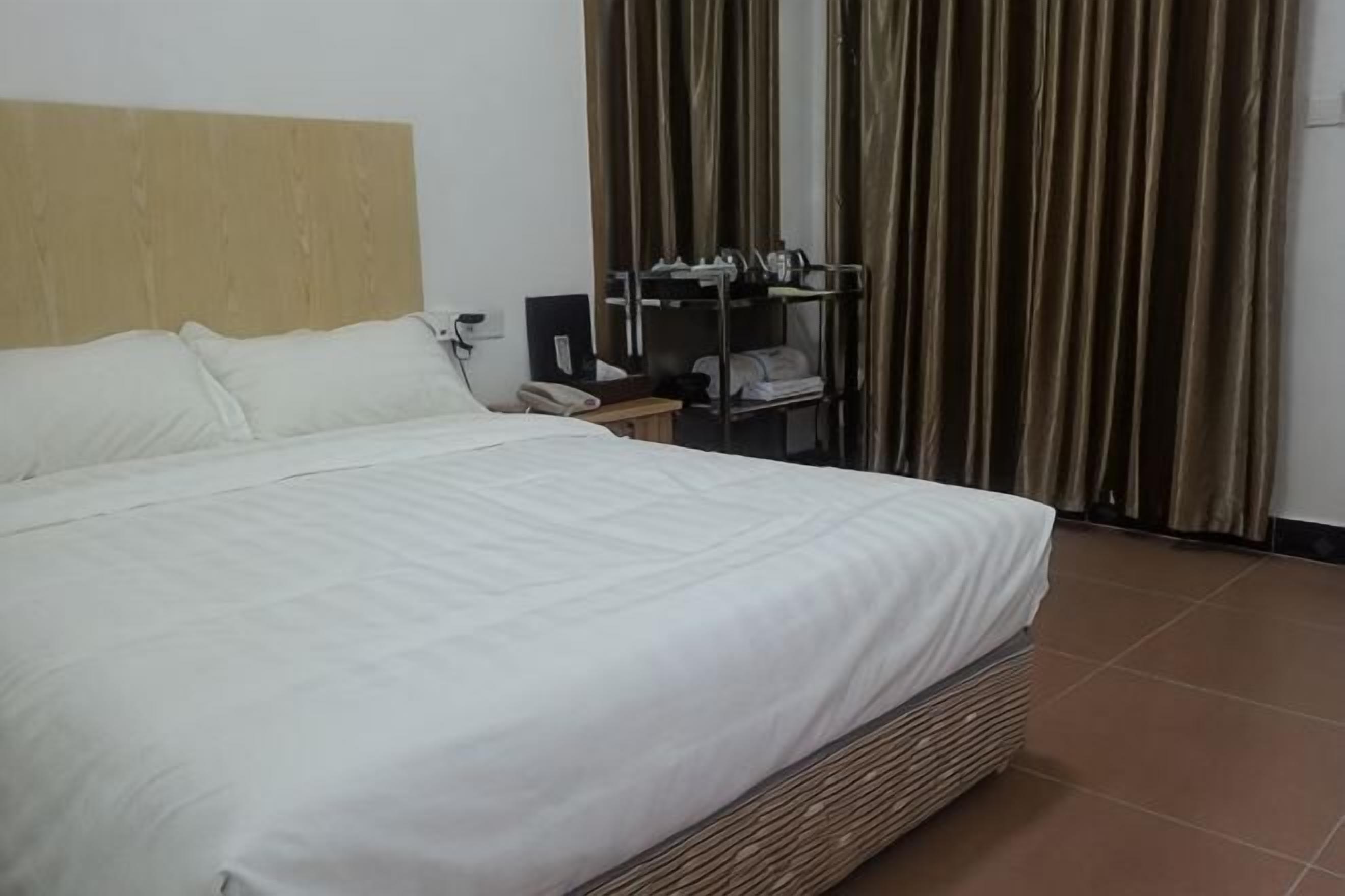 A hotel room with a large bed, a desk with a phone, and a wardrobe.