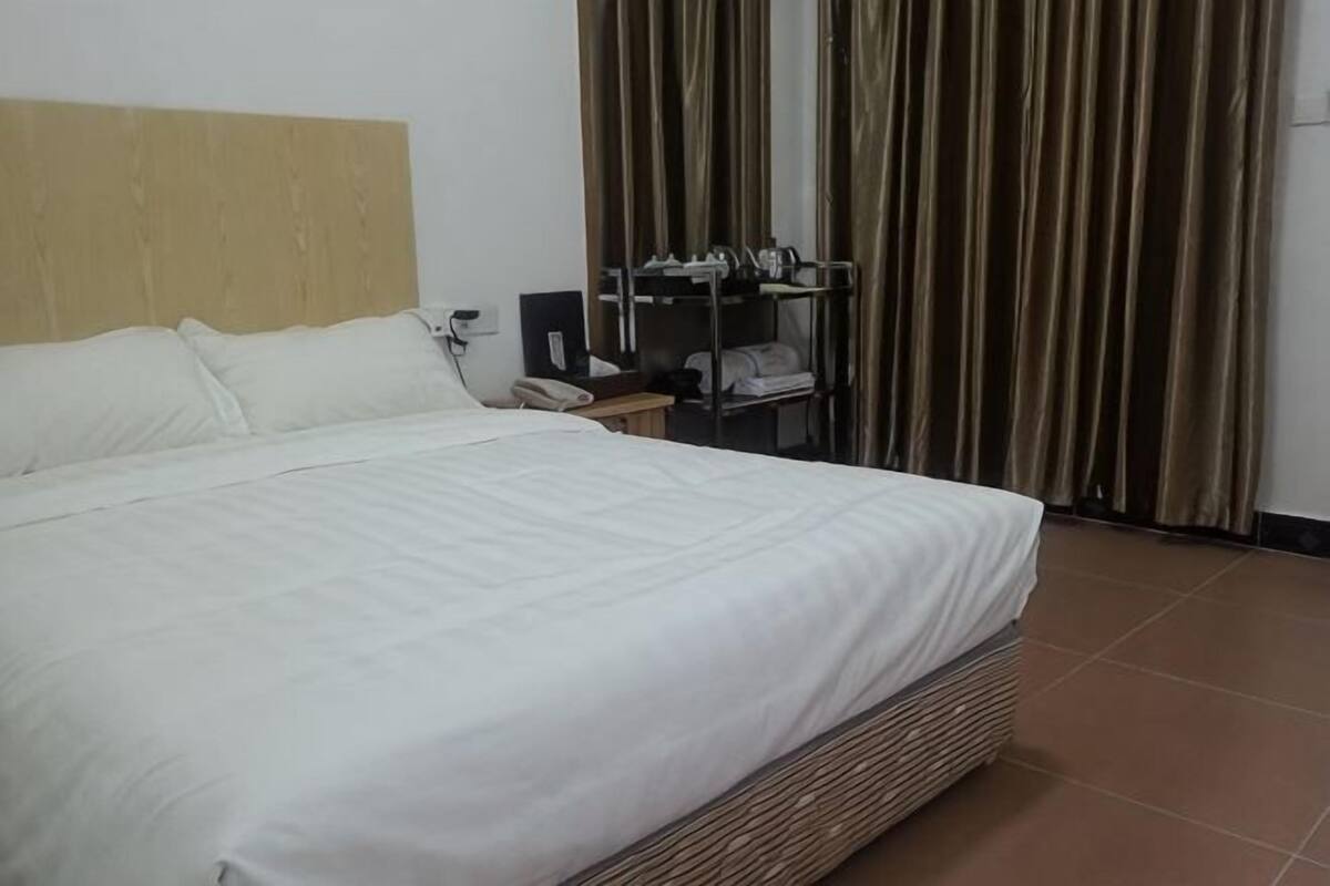 Een hotelkamer met een groot bed, een bureau met telefoon en een kledingkast.