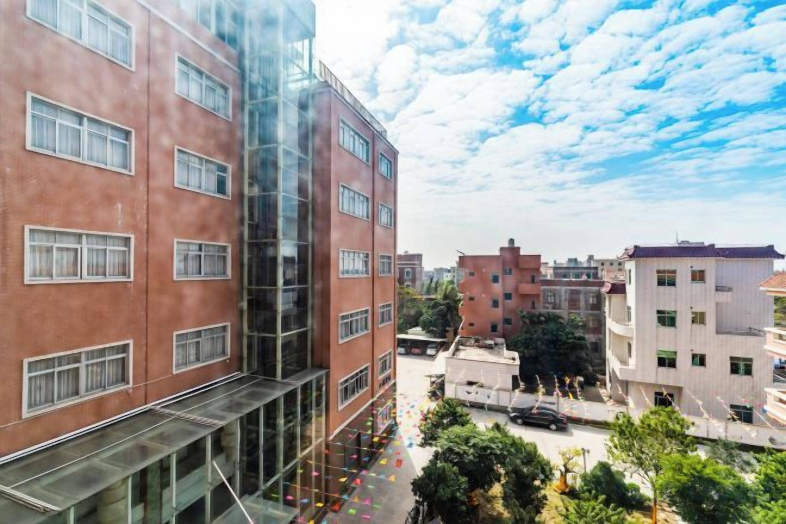 A multi-story building with a glass facade and a courtyard with trees.