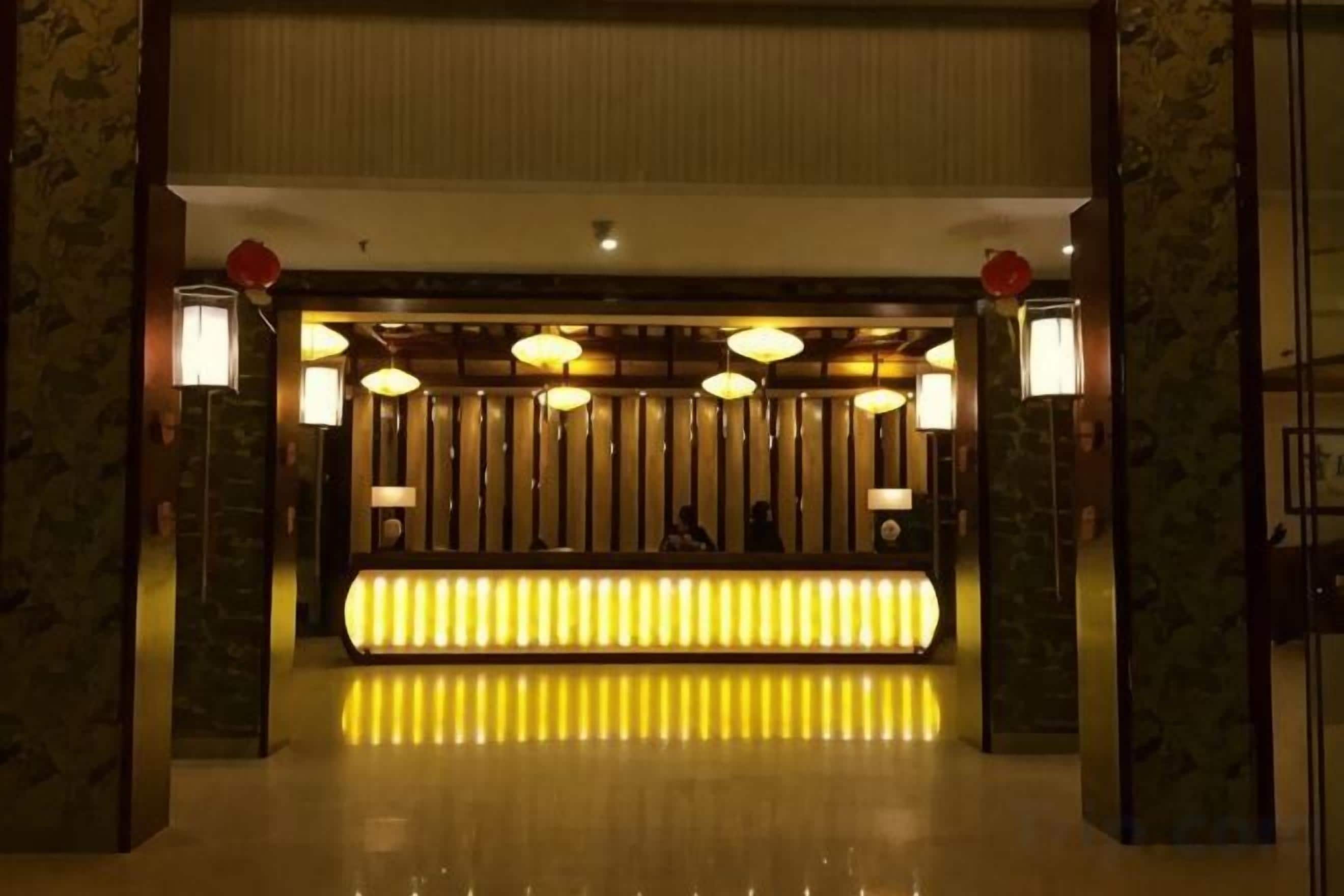 A reception area with a reception desk, multiple lamps, and a patterned wall.