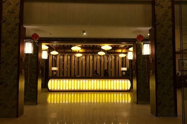 A reception area with a reception desk, multiple lamps, and a patterned wall. - Liujingtai Garden Hostel (Wuchuan)
