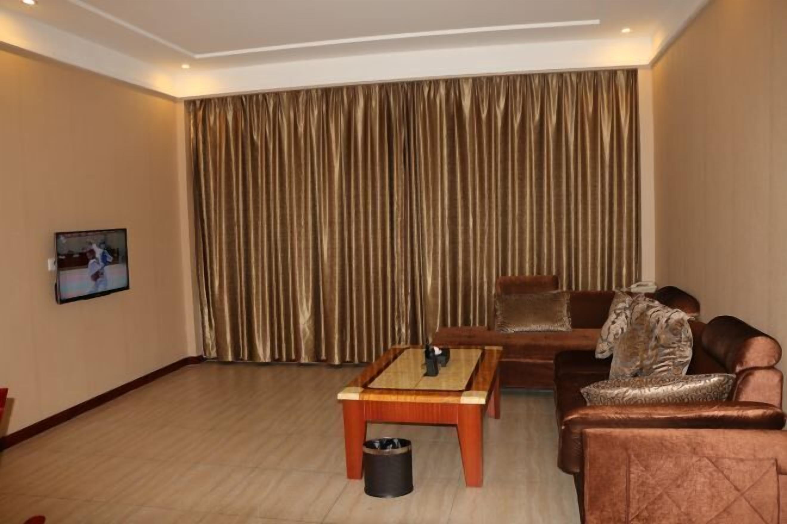 A living room with a sofa, a coffee table, and a television on the wall.
