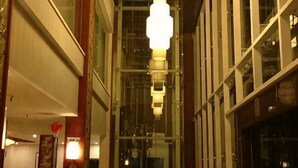A corridor with hanging lights, a glass wall, and a door on the left. - Liujingtai Garden Hostel (Wuchuan)