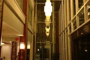 A corridor with hanging lights, a glass wall, and a door on the left. - Liujingtai Garden Hostel (Wuchuan)