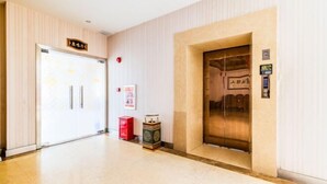 A hotel lobby with a reception desk, a red trash bin, and an elevator. - Liujingtai Garden Hostel (Wuchuan)